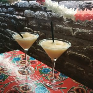 two cocktail glasses with frozen margaritas and black straws