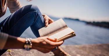 woman reading book near water