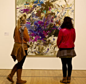 interior of museum, two women looking at modern painting