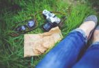 legs with blue jeans in grass, with camera, sandwiches and sunglasses