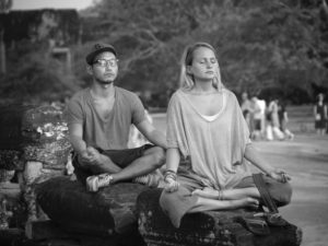 two people sitting in lotus position and breathing with eyes closed