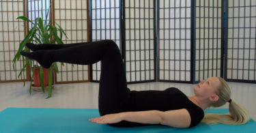 blonde lady doing pilates exercise on mat