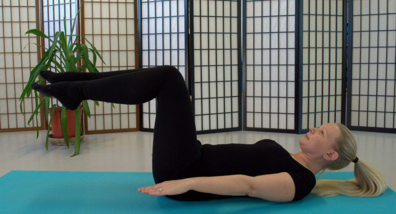 blonde lady doing pilates exercise on mat