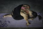 lady in dark environment in yoga pose on purple yoga mat