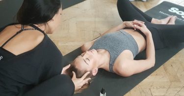 yoga teacher and student on floor