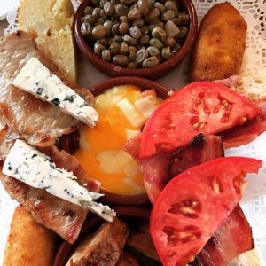 Mix of food in a plate with some tomatoes, cheese, meat and bread