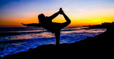 lady doing yoga exercise on beach when sun has just set