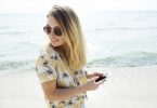 lady in floral blouse and sunglasses with phone in her hands