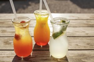 three cocktails with straws on wooden table