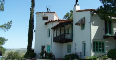large white spanish house with trees