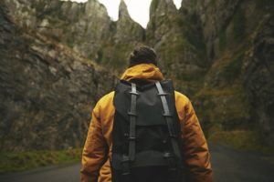 hiker with yellow jacket and backpack in mountains