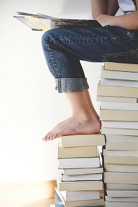 person sitting on pile of books