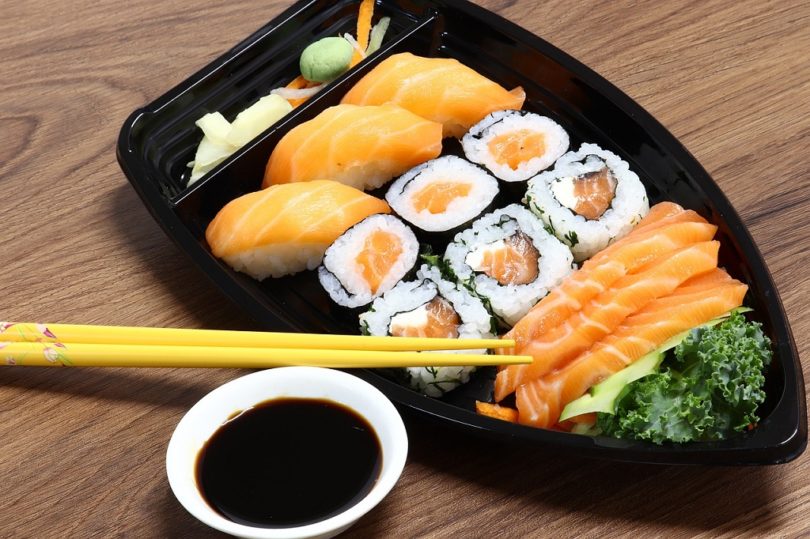 plate of salmon sushi with chop sticks and soya sauce