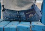 passport in back pocket of person sitting on blue bench