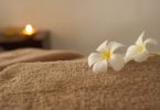 beige towel with white flower and candle