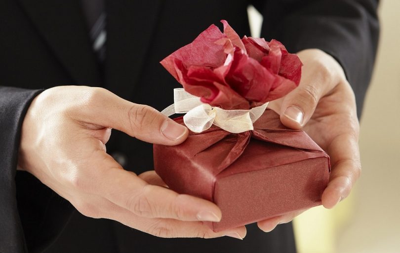 gift in red wrapping paper in hands man