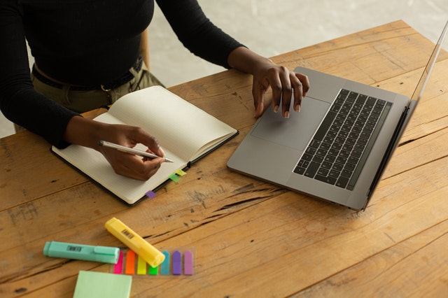 lady sits at wooden table with laptop