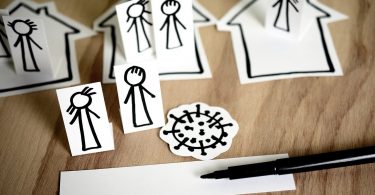 dibujos de personas y casas y un virus sobre una mesa de madera y un rotulador negro