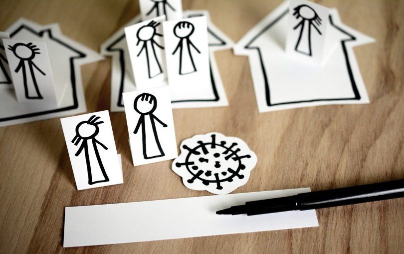 dibujos de personas y casas y un virus sobre una mesa de madera y un rotulador negro