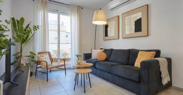 Salón de un apartamento, donde en la parte superior central se distingue un aparato de aire acondicionado.
