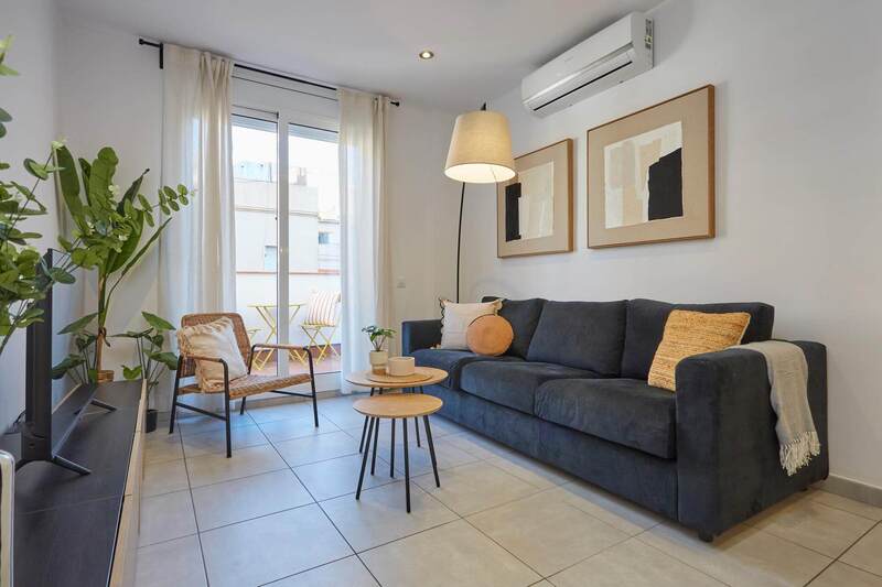 Salón de un apartamento, donde en la parte superior central se distingue un aparato de aire acondicionado.