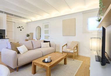 Salón reformado y completamente amueblado con suelo de parquet y colores claros.