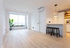 Salón reformado con suelo de parquet y colores claros.