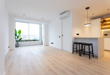 Salón reformado con suelo de parquet y colores claros.