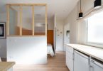Habitación reformada con suelo de parquet y colores claros con una cama al fondo.