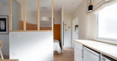 Habitación reformada con suelo de parquet y colores claros con una cama al fondo.