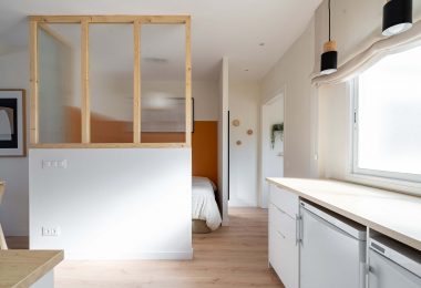 Habitación reformada con suelo de parquet y colores claros con una cama al fondo.