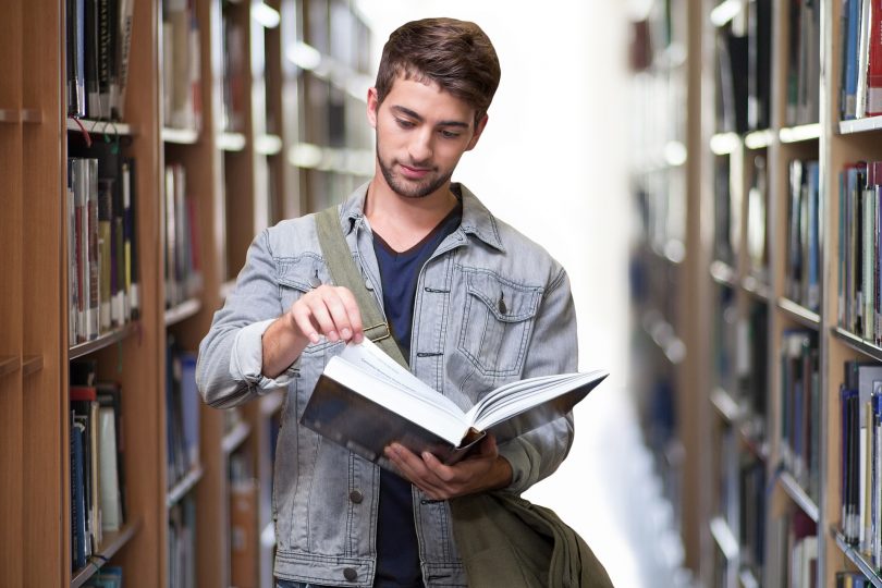 etudiant lisant un livre dans une bibliotheque