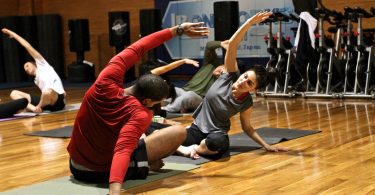 deux personnes s'étirant dans une salle de gym