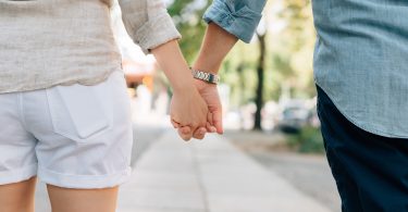 homme et femme se tenant la main dans la rue