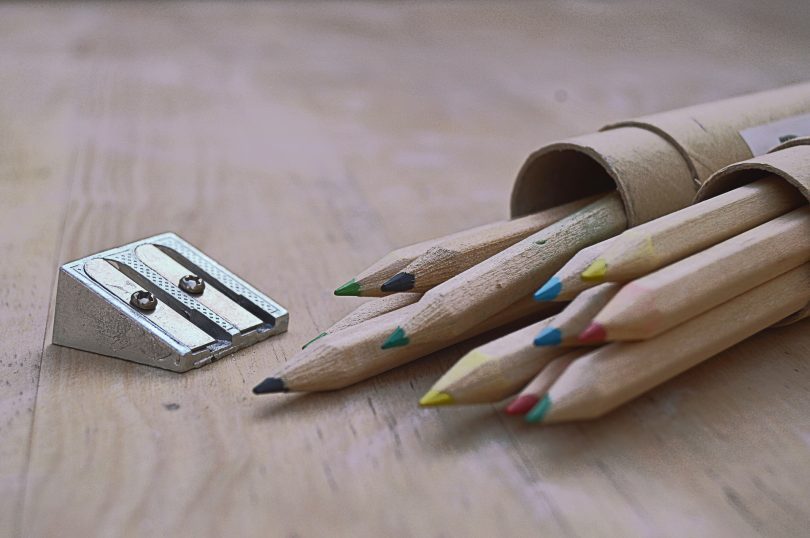 crayons de bois posés sur une table avec un taille-crayon