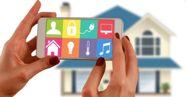 femme tenant une tablette devant une maison
