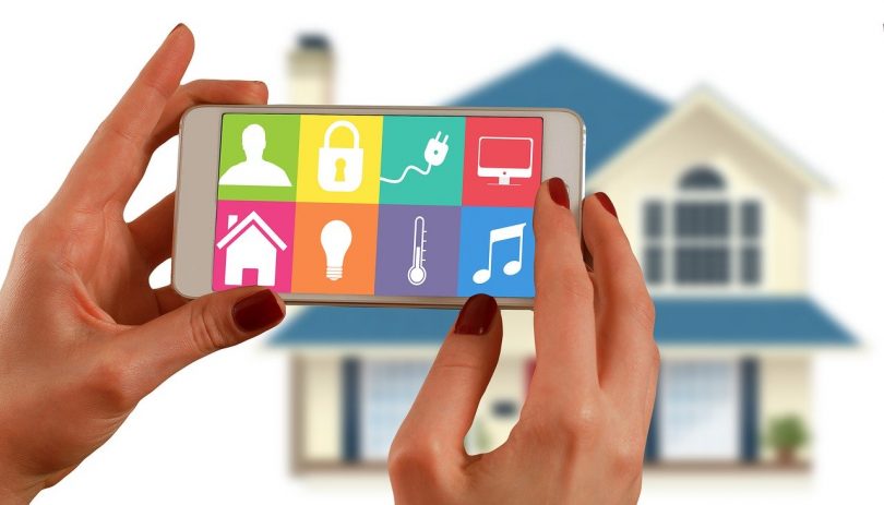 femme tenant une tablette devant une maison