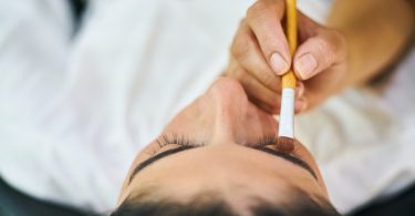main peignant la paupière d'une femme