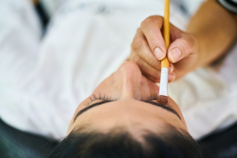 main peignant la paupière d'une femme