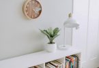Meuble blanc et horloge en bois sur mur blanc