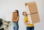 couple portant des cartons de déménagement