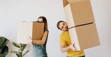 couple portant des cartons de déménagement