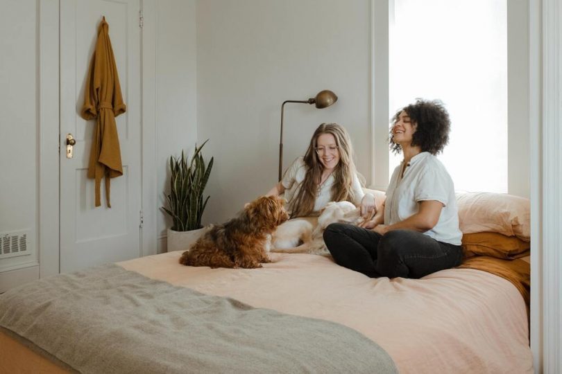 deux femmes assises dans une chambre avec un chien