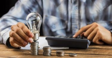 main tenant une ampoule sur des pièces de monnaie