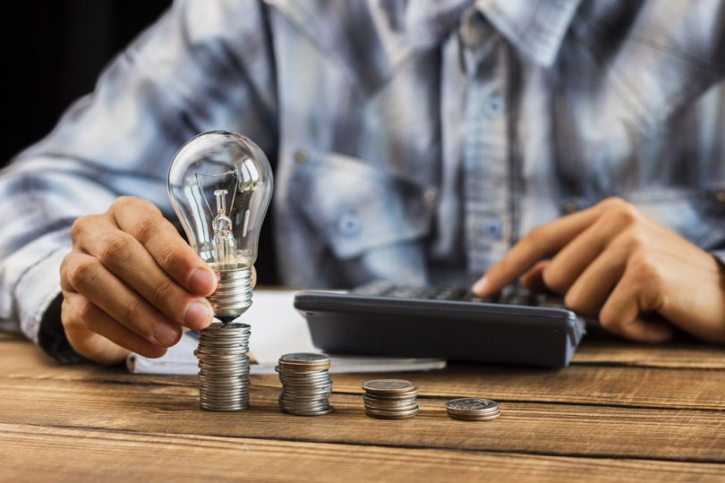 main tenant une ampoule sur des pièces de monnaie