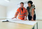 un homme et une femme devant des plans de construction