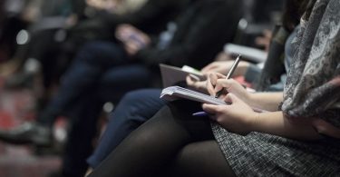 Estudiant prenent apunts en una xarrada informativa