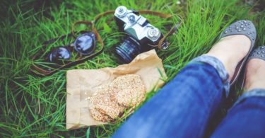 legs with blue jeans in grass, with camera, sandwiches and sunglasses