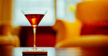 vermouth in glass on bar with orange chair in background