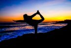 lady doing yoga exercise on beach when sun has just set
